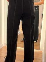 Pantalón de jean negro de corte recto y relajado, con costuras a contratono en color blanco. Presenta cintura con botón y cierre, bolsillos laterales y ruedo desflecado.