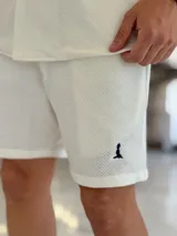 Bermuda blanca de tejido texturizado, con pequeño bordado oscuro en la parte inferior izquierda.