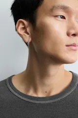 Camiseta de manga larga con cuello redondo, confeccionada en tejido de algodón con textura tipo waffle y efecto lavado. Presenta un corte relajado con puños en rib y bajo irregular.
