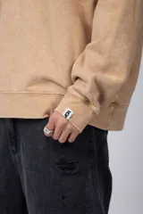 Buzo de cuello redondo con efecto de teñido artesanal acid wash. Presenta un corte oversize, mangas largas con puños acanalados y etiqueta pequeña en el puño izquierdo.