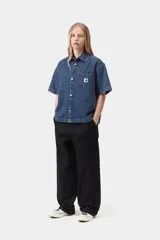 Camisa de denim de algodón celeste, de corte holgado y mangas cortas, con cierre frontal de botones metálicos y un bolsillo aplicado en el pecho con etiqueta de la marca.