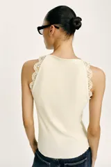 Top negro de punto rib con cuello halter, sin mangas y detalles de encaje a tono en las sisas.