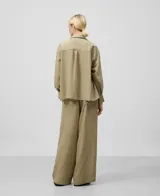 Camisa color verde claro con rayas verticales, cuello bowling, manga larga caída, bolsillo de parche en el pecho, puños abotonados y cierre frontal con botonadura central.