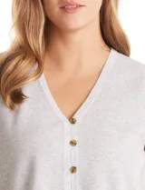 Chaleco de punto color beige, con escote en V pronunciado y cierre frontal con botones a tono. Diseño sin mangas y corte recto.