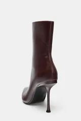 Botín de caña baja con acabado en punta y tacón alto fino. Presenta cierre mediante cremallera lateral.