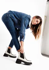 Botinetas de cuero vacuno color blanco tiza, con elásticos laterales negros, suela de goma antideslizante y plataforma con taco cuadrado.