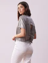 Blusa gris metalizada de tejido lurex, marca June & Hudson, con cuello redondo y ruedo con nudo en la espalda.