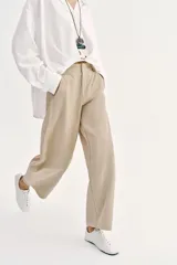 Pantalón barrel color azul marino, de tiro bajo, pernera holgada con diseño redondeado que se estrecha hacia el tobillo, con bolsillos delanteros y cierre frontal.