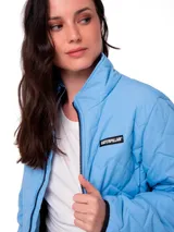 Chaqueta acolchada de corte regular, color celeste, con cierre frontal, cuello alto y bolsillos laterales. Presenta un parche con el logo de la marca en el pecho y puños con elástico.