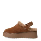 Zueco de mujer color marrón camel, confeccionado en gamuza con forro interior de piel sintética. Presenta una suela de plataforma dentada en tono marrón y una tira trasera ajustable con cierre de velcro.