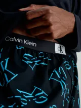 Conjunto de pijama Calvin Klein compuesto por una remera de manga larga negra con logo CK en el pecho y un pantalón largo negro con estampado del logo CK en azul.