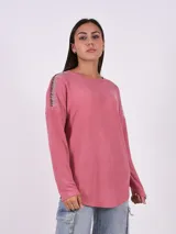 Blusa de tejido de punto color rosa viejo, con cuello redondo y mangas largas. Presenta apliques de strass en los hombros.