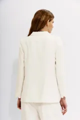 Saco de vestir color blanco hueso, corte recto y holgado, con solapas de muesca, un botón frontal y bolsillos de parche.