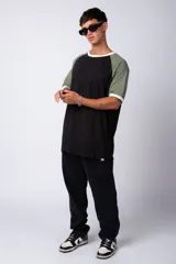 Remera estilo raglán color blanco en el cuerpo, con mangas en tono tostado y ribetes en color verde militar en el cuello y los puños.