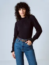 Camiseta negra de manga larga con cuello alto fruncido y puños elásticos con volados.