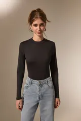 Body de manga larga al cuerpo, confeccionado en poliamida, con cuello a la base y cierre inferior con broches.