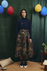 Falda midi de corte amplio con cintura elastizada y frunces laterales, confeccionada en tejido tipo gobelino con estampado floral sobre fondo azul.