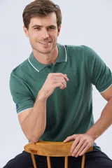 Remera polo de piqué manga corta, color verde oscuro, con cierre frontal de botones y detalles de líneas en contraste en el cuello y los puños.