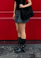 Botas de caña media color negro, con suela track y correas con hebilla plateada alrededor de la caña. El material es símil cuero.