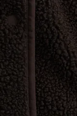 Chaleco de tejido sherpa (borreguito) color marrón oscuro, con cuello redondo y cierre frontal de botones. Presenta ribetes de cinta a tono y bolsillos redondos en la parte delantera.