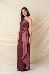 Vestido largo asimétrico de encaje color bordó, con un solo bretel y detalle de apliques florales en hombro y cintura. Presenta una pieza lateral de tafeta que cae desde el escote y un tajo pronunciado en el costado.