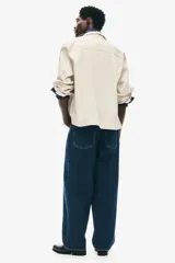 Jean de corte baggy confeccionado en denim de algodón rígido, con diseño de cinco bolsillos, tiro bajo y piernas amplias de silueta redondeada.