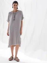 Vestido midi de lino color gris con cuello redondo, mangas cortas y ruedo asimétrico con flecos.