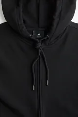 Campera negra con capucha forrada en punto, cierre frontal, cordón ajustable y bolsillos laterales. Puños y bajo acanalados.
