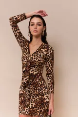 Vestido corto ajustado al cuerpo, con estampado animal print, escote en V, mangas largas y volados frontales.