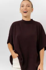 Sweater de tejido de punto color negro, con cuello semi alto y mangas cortas amplias. Presenta una silueta relajada y caída fluida.