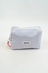 Neceser de tela con estampado de cuadros vichy en tonos lila y blanco. Cuenta con cierre superior y una pequeña tira de agarre en color rosado. Incluye una etiqueta frontal con el logo de la marca.