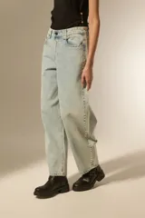 Pantalon de jean estilo baggy, color celeste lavado, con detalle de tachas metálicas en los bolsillos delanteros y a lo largo de las costuras laterales. Presenta un corte ancho y tiro bajo.