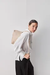 Camisa blanca de manga larga con textura suave y caída liviana, cuello camisero, puños anchos y fruncidos sutiles en los hombros.