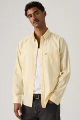Camisa de manga larga color amarillo claro, con cuello camisero, cierre frontal de botones y un bolsillo aplicado en el pecho con etiqueta roja de la marca.