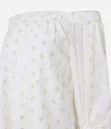 Blusa de tricolina blanca con estampado de lunares dorados en foil, escote descubierto estilo hombro a hombro y mangas largas abullonadas con puños elásticos.