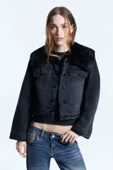 Campera de denim negro con forro de piel ecológica en el cuerpo y mangas con matelassé. Presenta doble cuello, uno de ellos desmontable, cierre frontal con botones metálicos y bolsillos tipo plaqué.