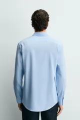 Camisa de corte slim fit, color negro, con cuello italiano, manga larga con puños abotonados y cierre frontal de botones. Confeccionada en tejido de fácil cuidado que minimiza la necesidad de planchado.