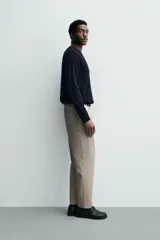 Pantalón de corte regular fit, color negro, confeccionado en tejido elástico. Presenta cintura elástica, cierre frontal con cremallera y botón, bolsillos laterales y bolsillos traseros de vivo.