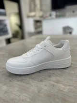 Championes urbanos de color blanco con diseño de corte bajo, puntera perforada y suela de goma al tono.