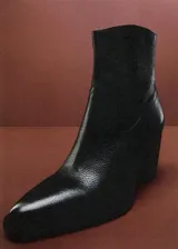 Botín de cuero vacuno color negro, con diseño de estilo western, punta fina y tacón bloque de 6,5 cm. Cuenta con cierre de cremallera lateral.