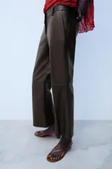 Pantalón de tiro medio confeccionado en 100% piel de color marrón, con diseño flare y costuras decorativas.