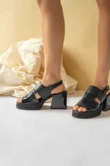 Sandalias de plataforma con taco cuadrado, confeccionadas en material sintético con acabado charol y textura tipo reptil. Cuentan con tira frontal ancha y ajuste con hebilla en el talón.
