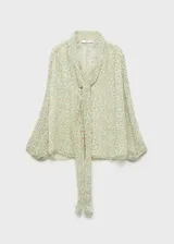 Blusa de gasa estampada con flores, de corte recto y diseño semitransparente. Tiene cuello pico con lazo, cierre frontal con botones y mangas largas con puños elásticos. Incluye forro interior.