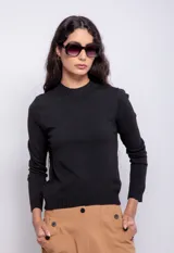 Polera de punto fino en color negro, de silueta entallada y manga larga. Presenta cuello media polera, puños y bajo con acabado acanalado.