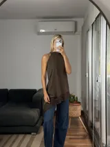 Musculosa de cuello alto con diseño irregular y bajo asimétrico, confeccionada en tela tipo cey con detalle de puntilla en el ruedo.
