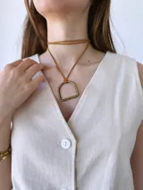 Colgante con cordón de cuero color camel y dije metálico dorado con forma de estribo.