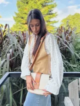 Chaleco beige de cuero con cuello en V y cierre frontal con botones.