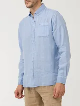 Camisa celeste de lino con cuello camisero, manga larga, cierre con botones y bolsillo en el pecho.