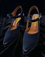 Sandalias de gamuza color verde oscuro con punta cerrada, pulsera al tobillo con hebilla metálica y tacón cuadrado.