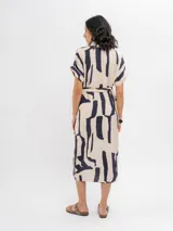 Vestido midi camisero de viscosa color beige con estampado abstracto en azul marino, manga corta, cuello camisero, cierre frontal con botones y lazo ajustable en la cintura.